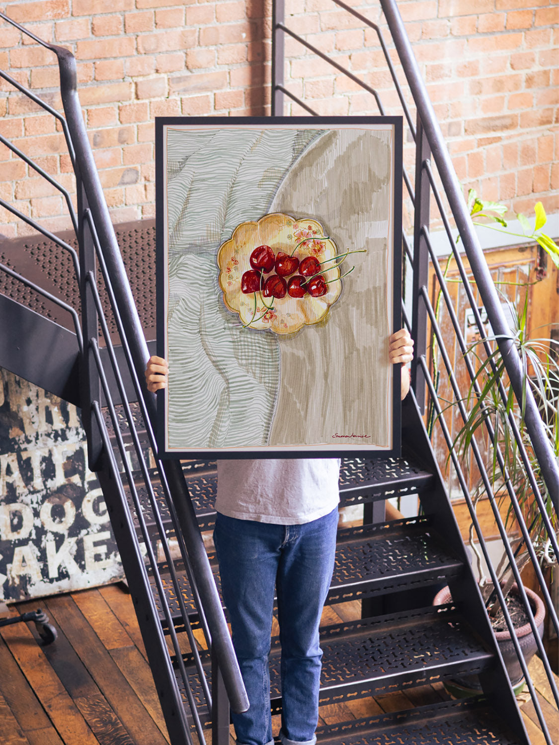 Fine art print "Cherries" by Emma Louise, framed in black, displayed in a cozy interior setting. |type=lifestyle|